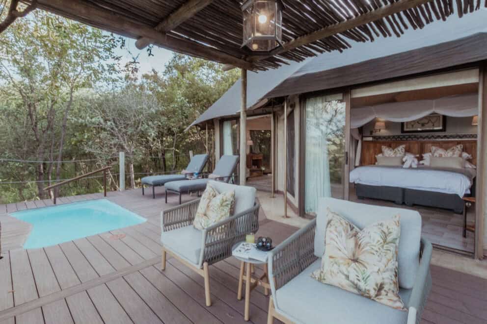 View of the bedroom suite deck, featuring a plunge pool and chairs at The Elephant Camp, Zimbabwe.
