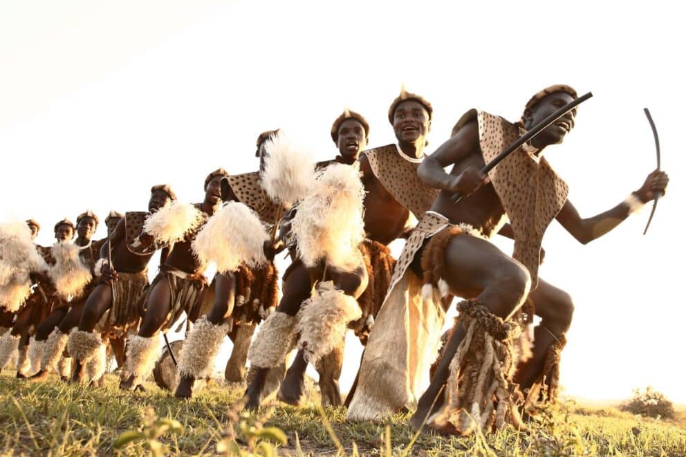 Zulu men in traditional attire participating in a ceremonial Zulu dance at &Beyond Phinda Rock Lodge, South africa.
