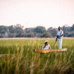 A tourist on a mokoro ride through the papyrus-lined water channel on Chief's Island at A&K Sanctuary Chief's Camp, Botswana.