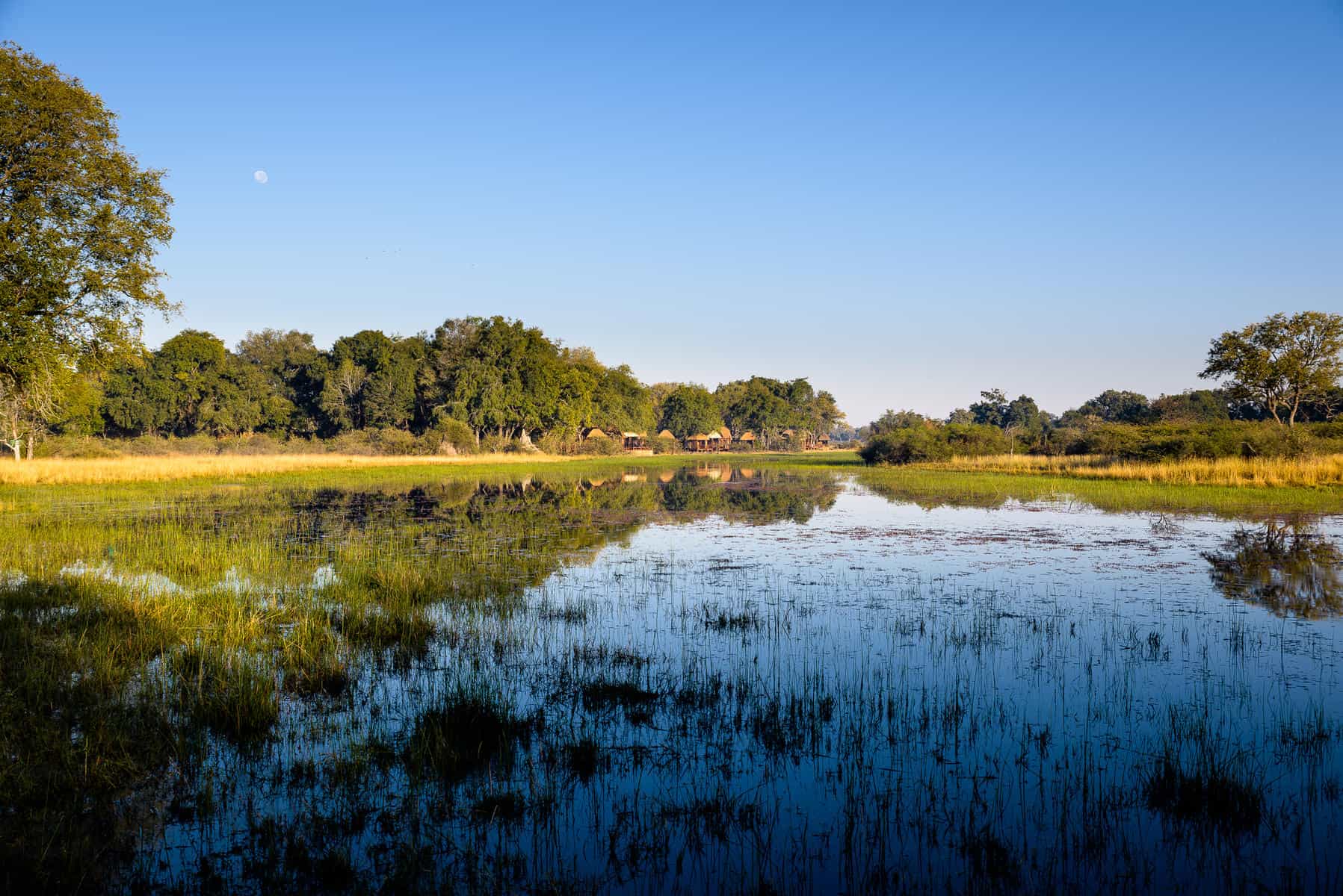 Exterior view of A&K Sanctuary Chief's Camp from a water channel on Chief's Island in the Okavango Delta at A&K Sanctuary Chief's Camp, Botswana.