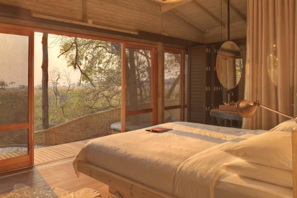 Golden sun rays gently streaming into a luxury bedroom at Sandibe Okavango Safari Lodge, Botswana.