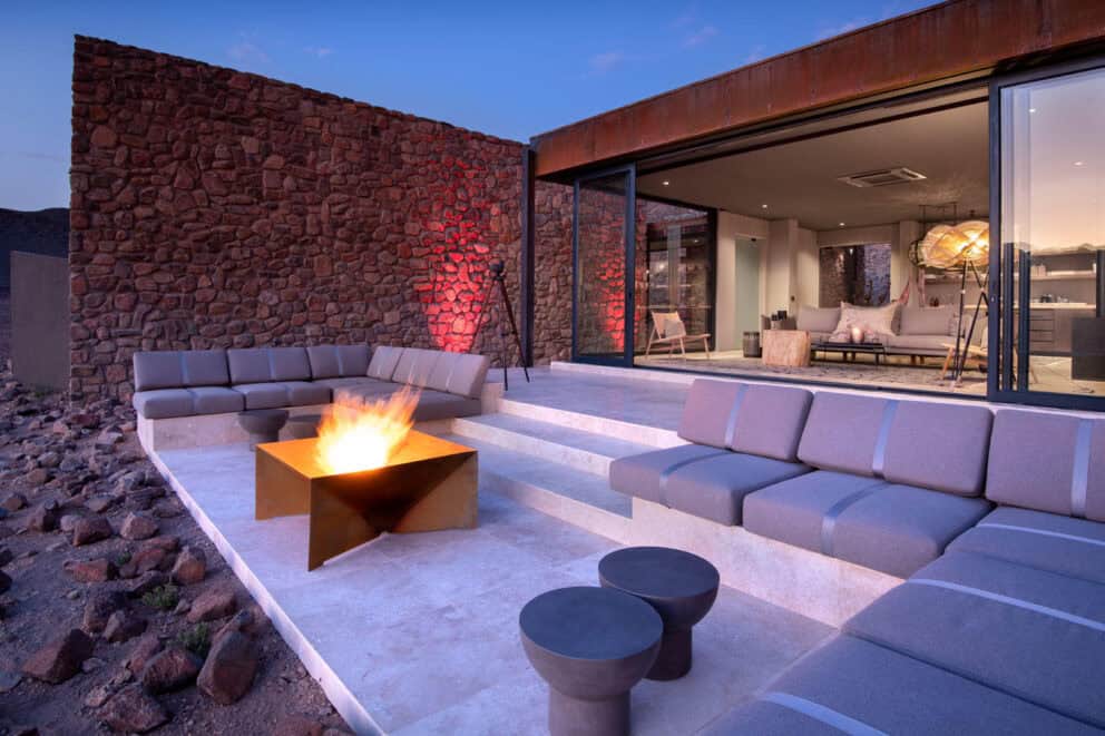 View of the sunken lounge, featuring a boma and comfy seating overlooking the desert landscape at Sossusvlei Desert Lodge, Namibia.