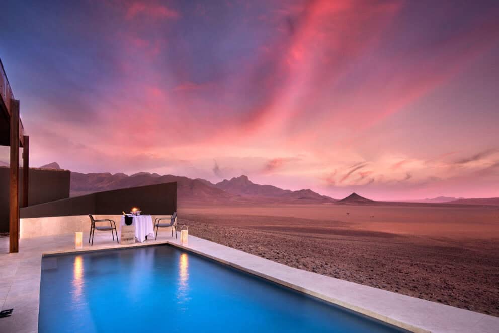 Private dinner by the pool under the beautiful dusk sky overlooking the desert landscape at Sossusvlei Desert Lodge, Namibia.