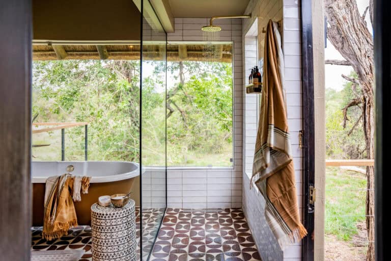 View of the bathroom, featuring a freestanding bath and large windows at Thornybush Game Lodge, South Africa.