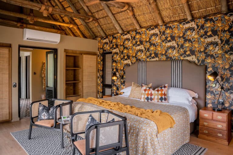 View of the luxury bedroom, featuring a king size bed and comfortable armchairs at Thornybush Game Lode, South Africa.