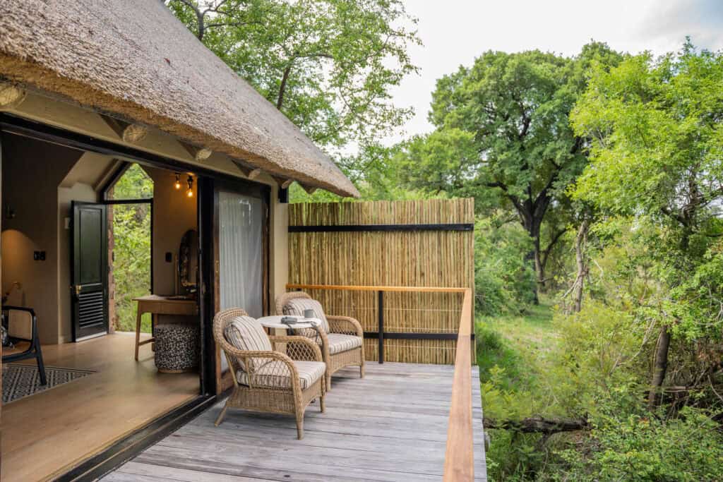View of the private balcony with two armchairs and sliding doors leading to the bedroom suite at Thornybush Game Lodge, South Africa.