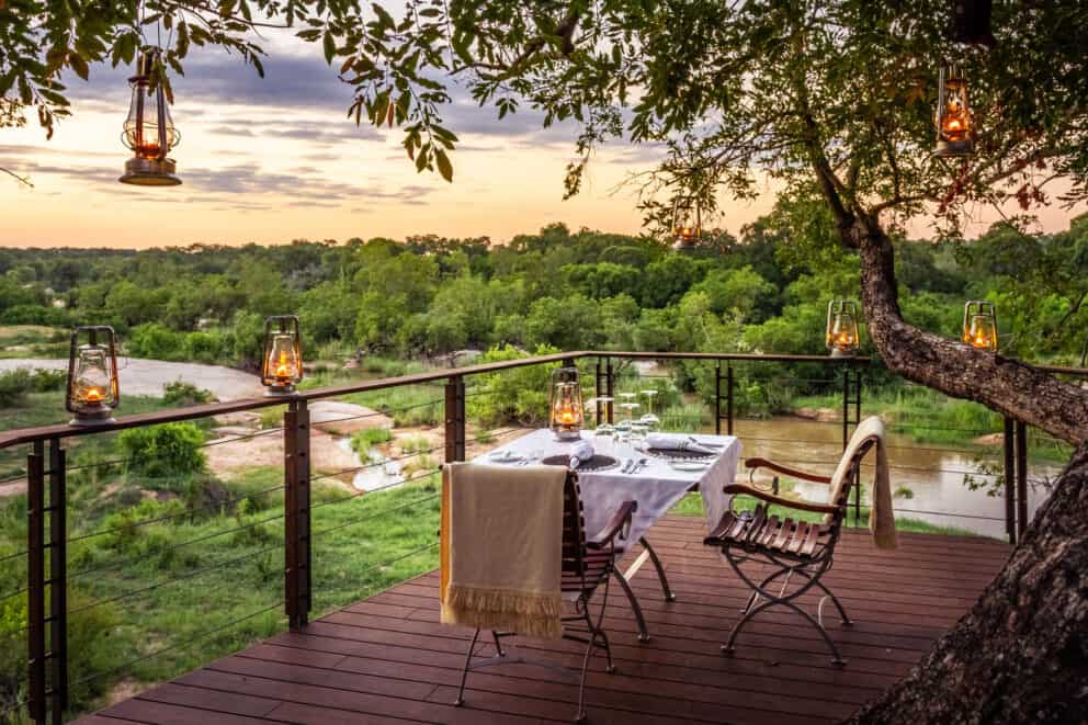 A dinner table set up on a private deck overlooking the Sabi Sand landscape at Dulini Leadwood, South Africa.