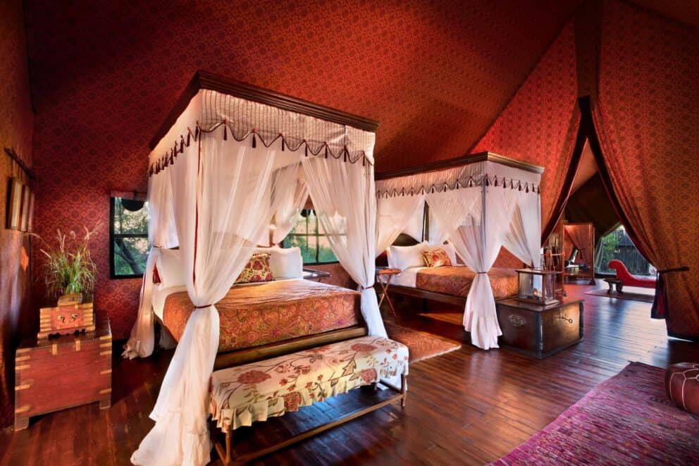 Four-poster beds in a red tent at Jack's Camp, a luxury safari lodge. 
