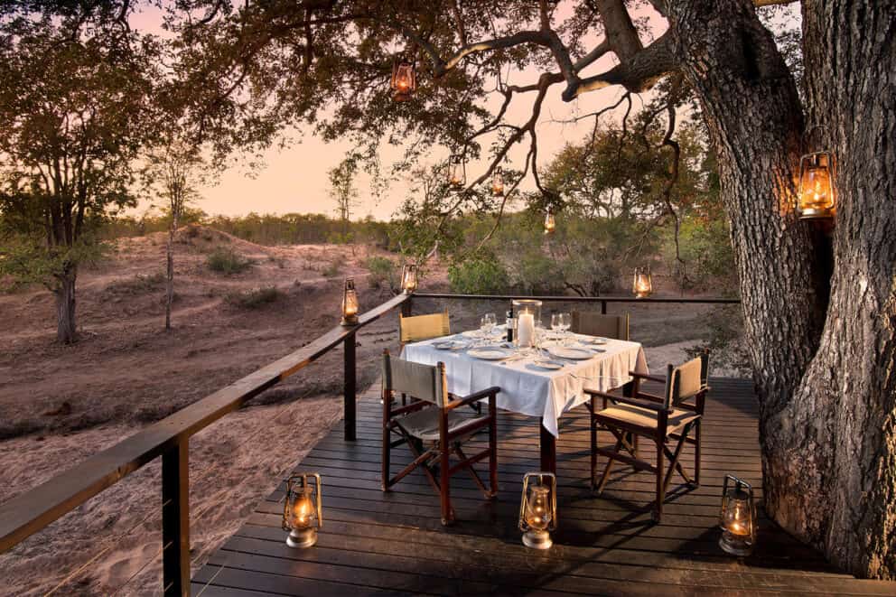 A candlelit private dining at sunset on an elevated deck overlooking the bush at Ngala Safari Lodge, Ngala Private Game Reserve.