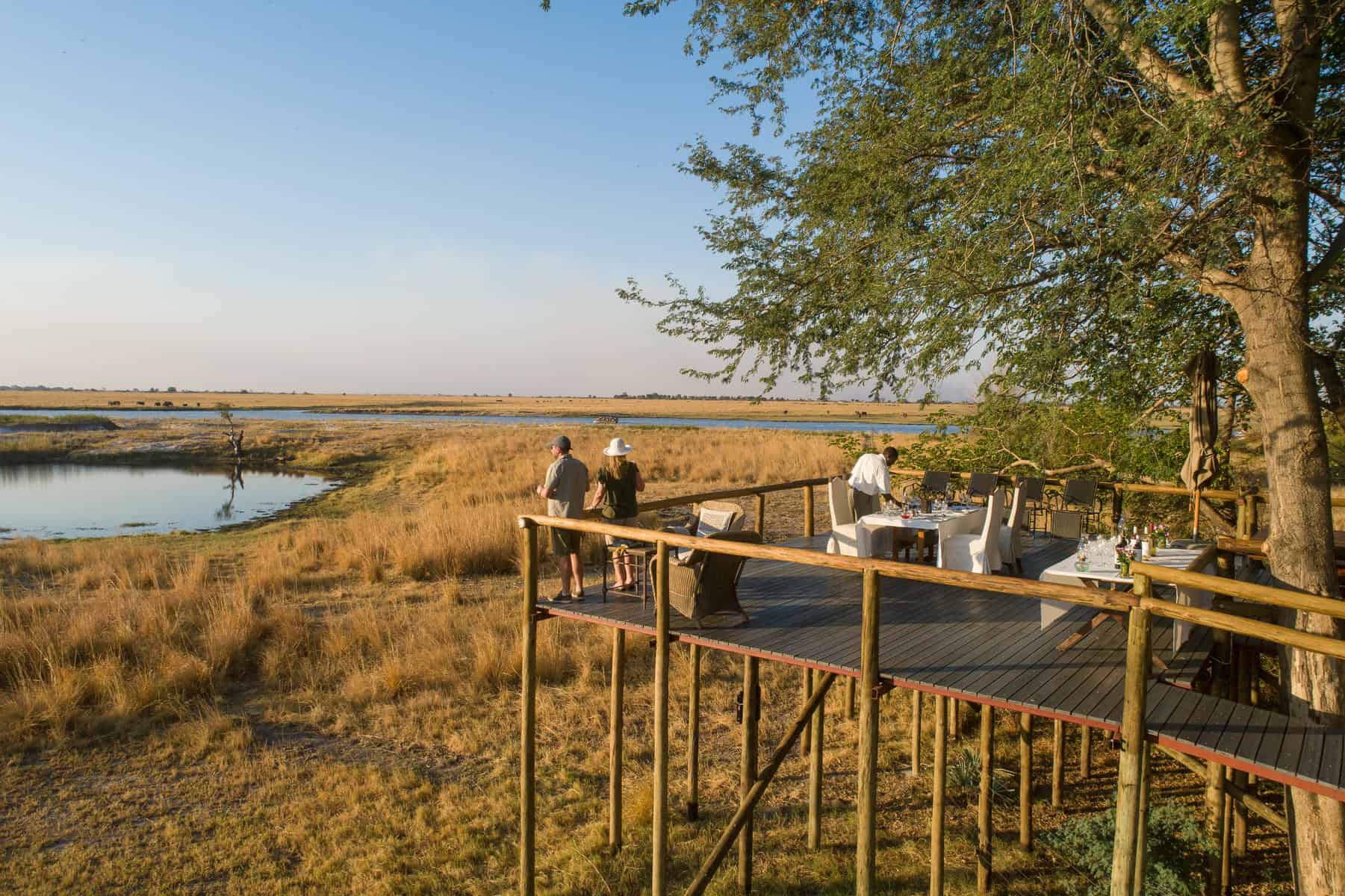 A couple standing on an elevated terrace overlooking the wetlands at Chobe Savanna Lodge, Zambezi Region.