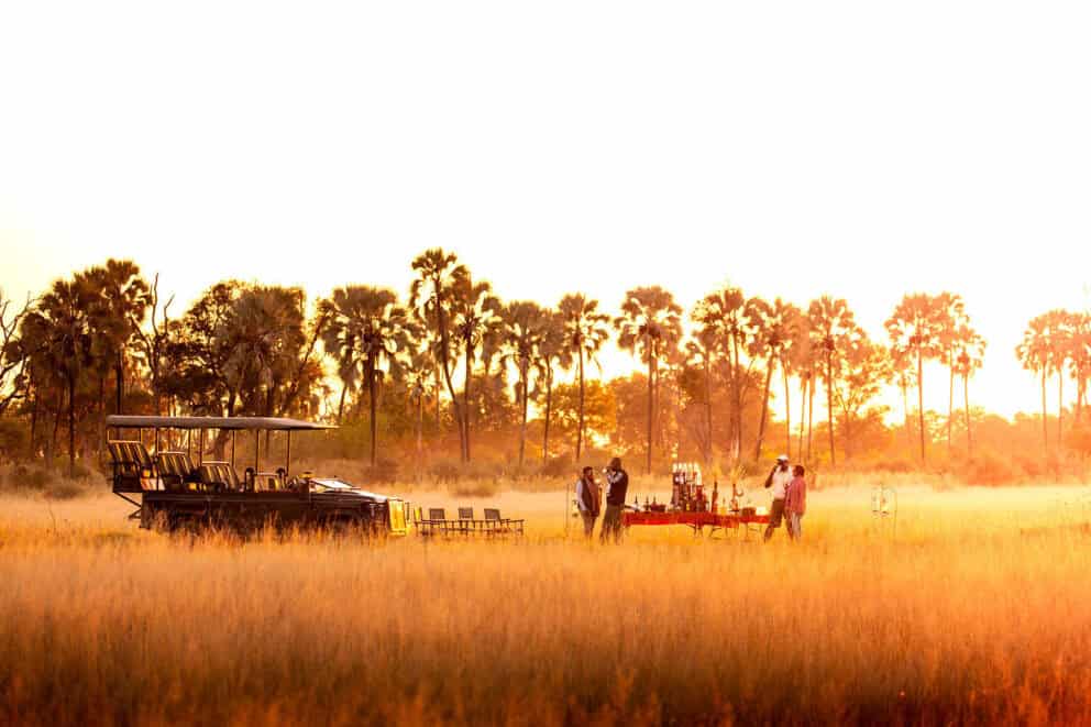 Guests at Wilderness Chitabe in Botswana enjoying sundowners at the 'Golden Hour'.