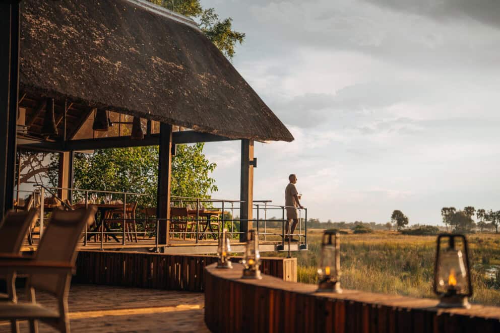 A tourist standing on an elevated deck overlooking the African landscape at Wilderness Chitabe, Botswana.