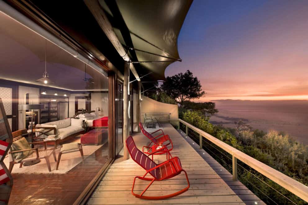 A sunset view of the bedroom and private balcony overlooking the Masai Mara at Angama Mara, Kenya.