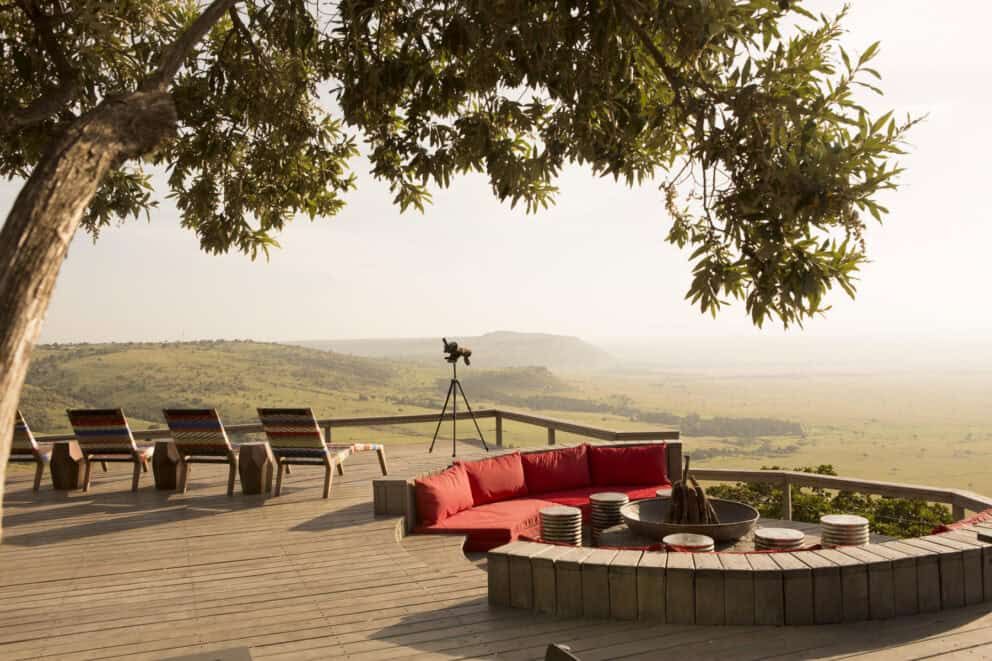 Elevated outdoor guest area with wooden decking and comfy seating overlooking the Masai Mara at Angama Mara, Kenya.