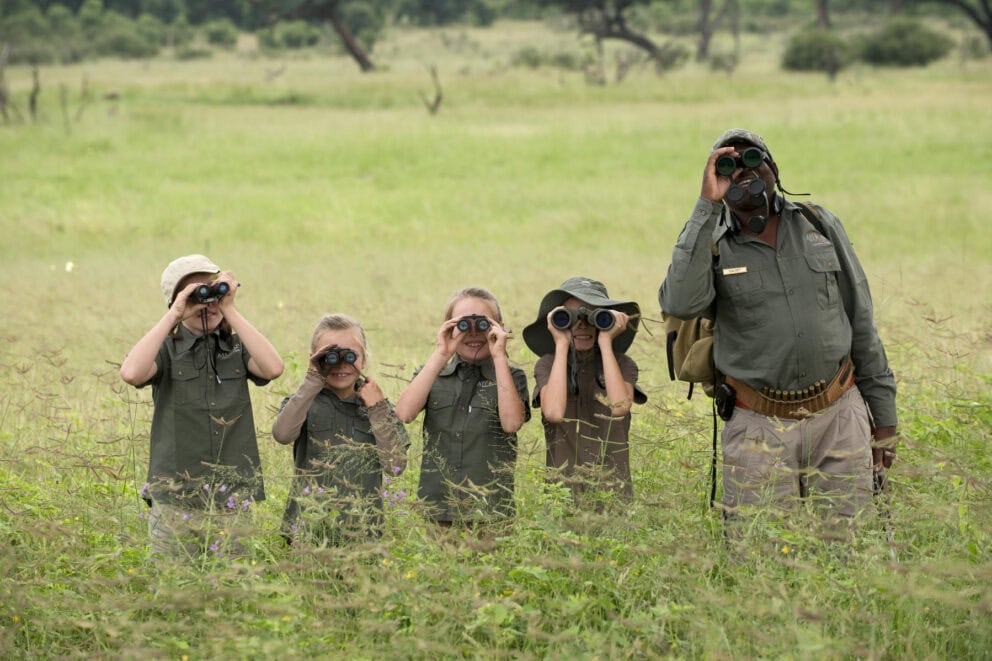 Children on a guided nature walk looking through their binoculars at Thorntree River Lodge, Zambia.