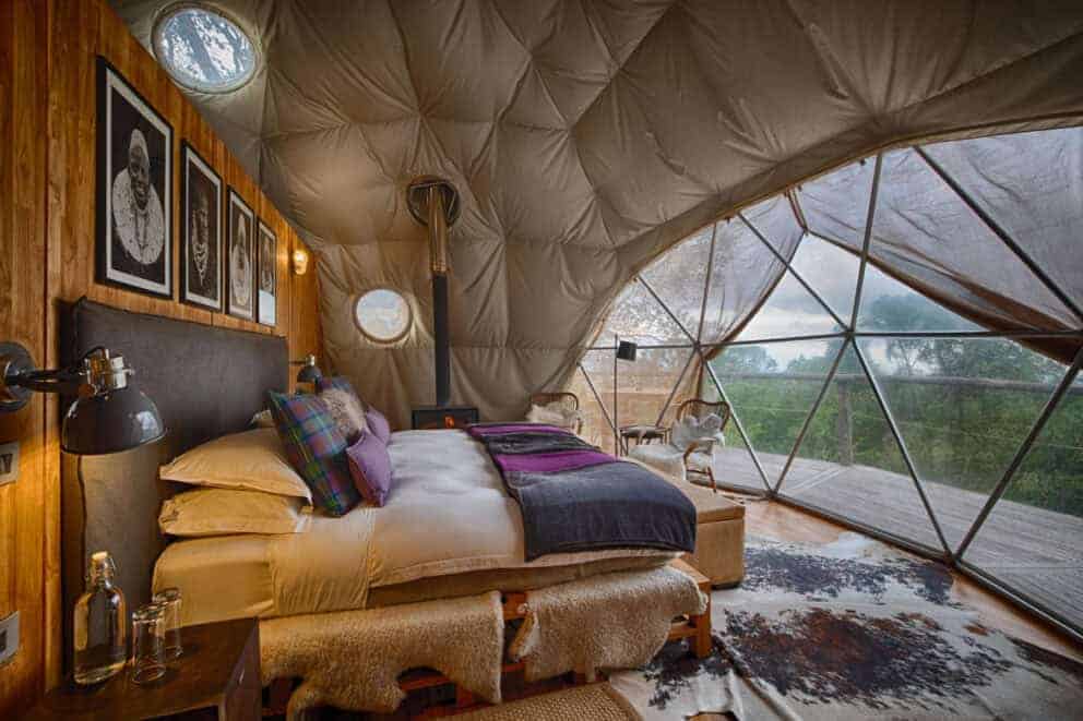 Interior view of the bedroom with the bed facing a window overlooking the African landscape in Ngorongoro Crater, Tanzania.