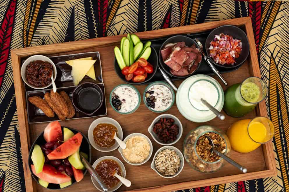  A breakfast board featuring a variety of fruit, toppings, plain yoghurt and juices at Grumeti Serengeti River Lodge, Tanzania.