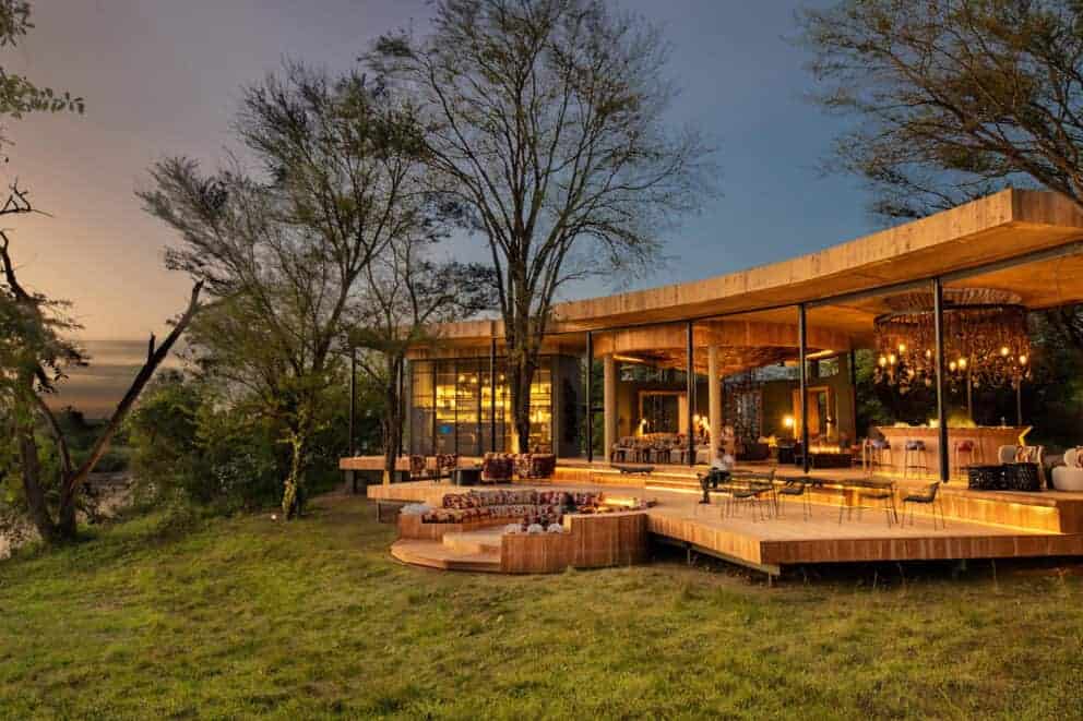 A guest sitting on the deck at dusk overlooking the African landscape at &Beyond Grumeti Serengeti River Lodge, Tanzania.