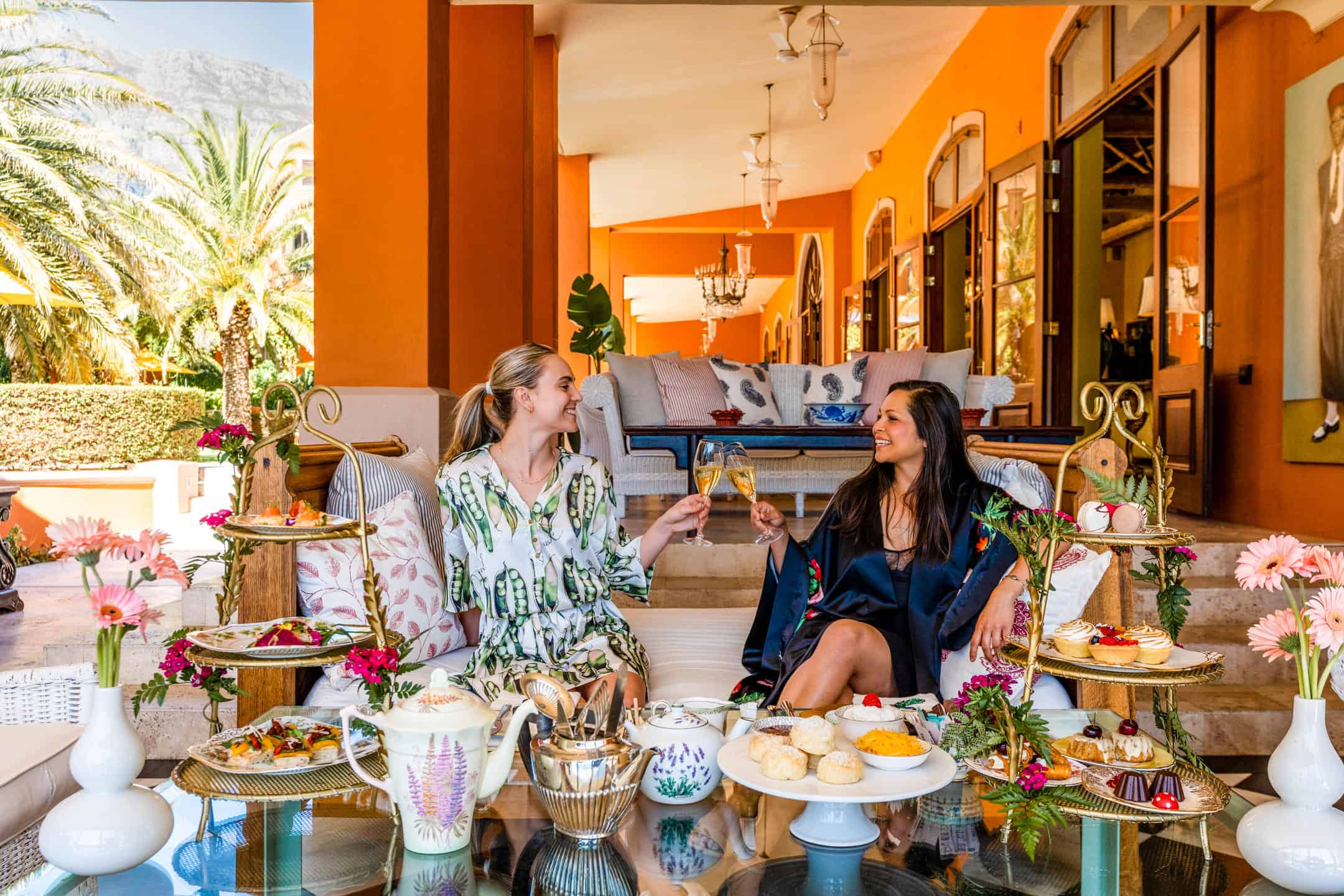 Two ladies enjoying afternoon tea treats and wine at La Residence, South Africa.