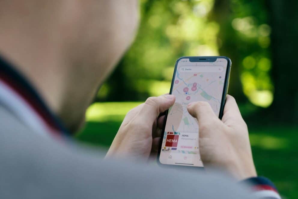 A person navigating Google Maps on a smartphone screen, displaying multiple saved location pins.