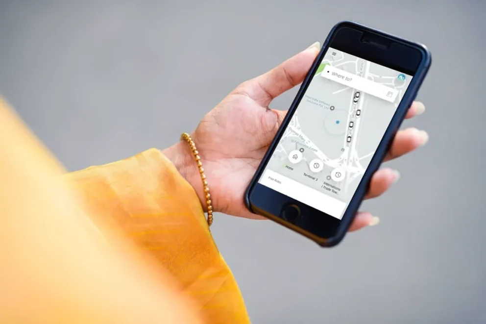 A woman holding a smartphone that's displaying the Uber app.