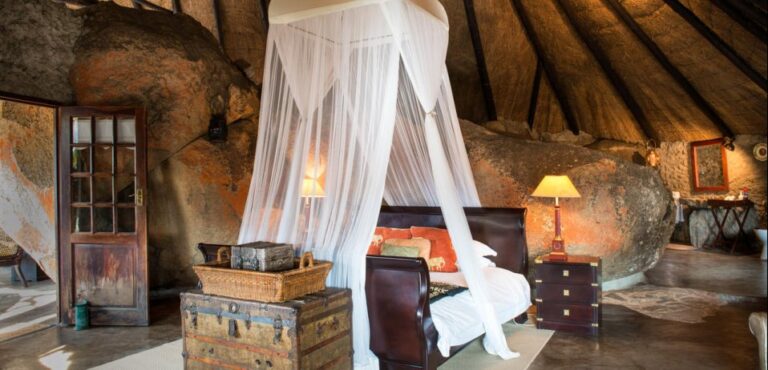 View of the bedroom with an elegantly drape luxury mosiquito netting over the bed at Amalinda Lodge, Zimbabwe.