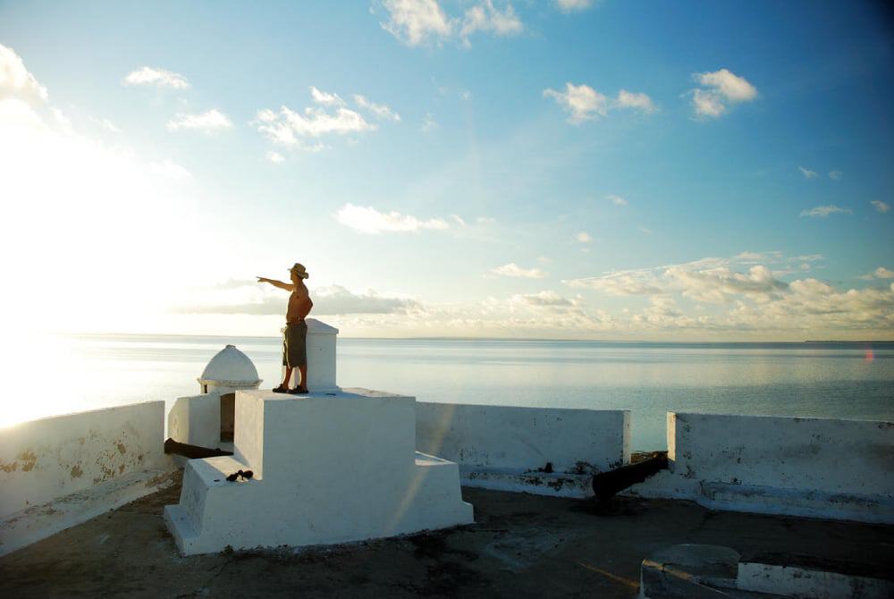 View of a man in a hat pointing over the horizon at sunset at Ibo Island Lodge in Mozambique.