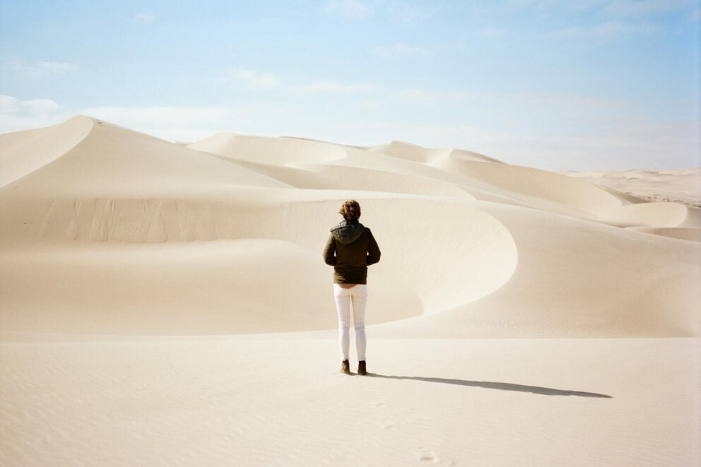 A traveller walking across the windswept sand dunes near Shipwreck Lodge, Skeleton Coast Namibia.