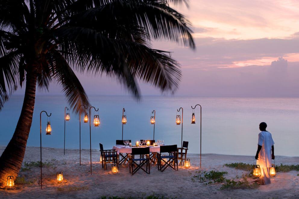 Dining on the beaches of Benguerra at sunset under a palm tree on an African Island beach holiday