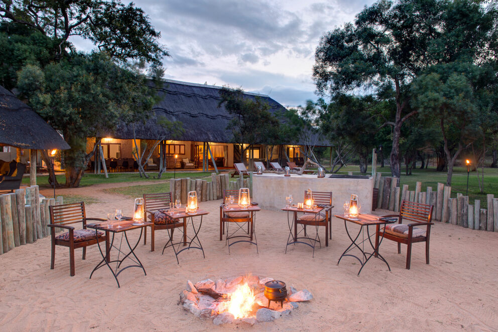Exterior view of Tintswalo Safari Lodge with a fire lit boma at dusk in the Manyeleti Private Game Reserve.