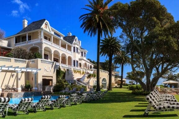 View of Ellerman House with green grass a palmtrees in Cape Town, and ideal location for a South Africa honeymoon