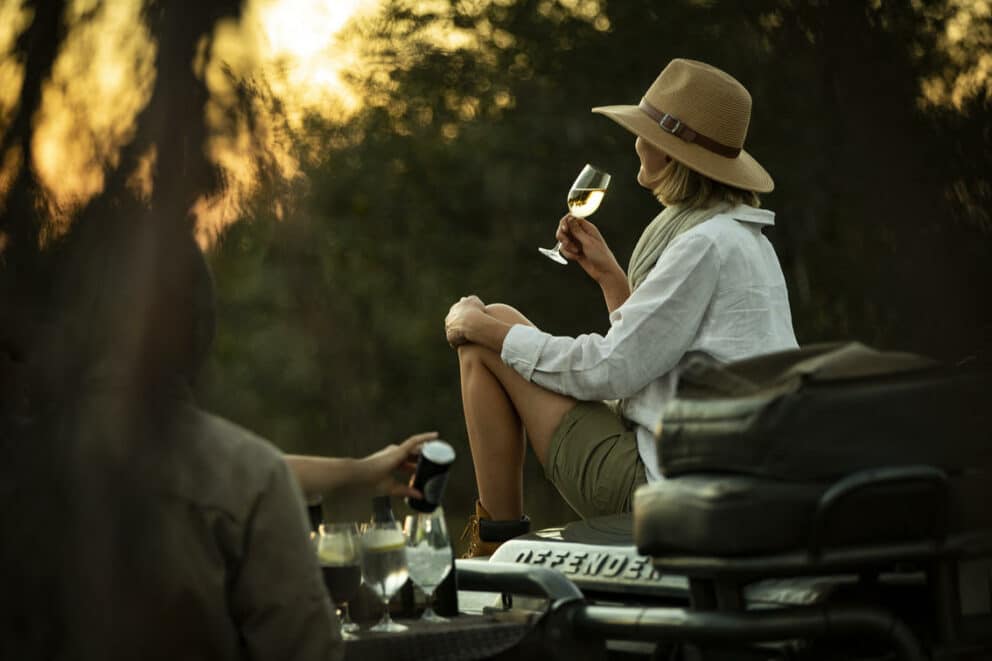 Woman having a sundowner on a game drive in Singita Concession