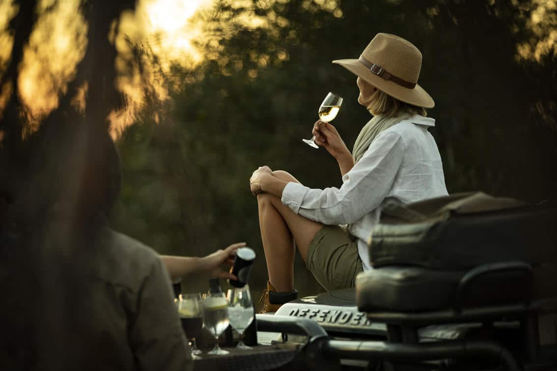 Woman having a sundowner on a game drive in Singita Concession