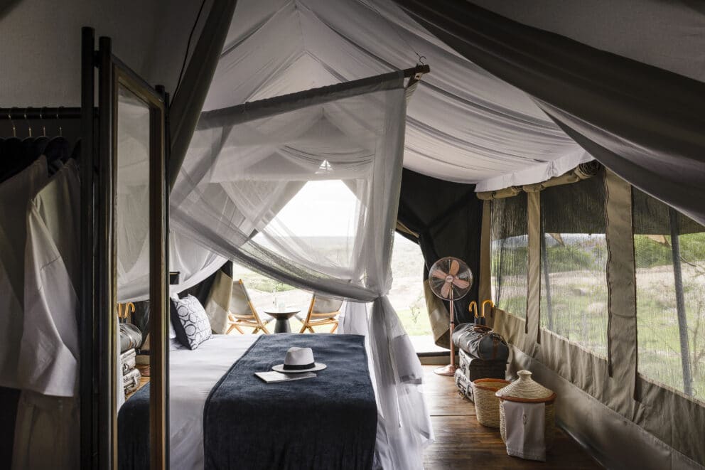 Interior view of a safari tent with a bed in it.