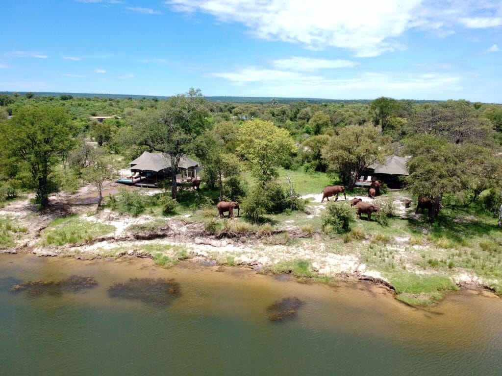 An aerial view of Old Drift Lodge in Zimbabwe, featuring elephants passing the lodge.