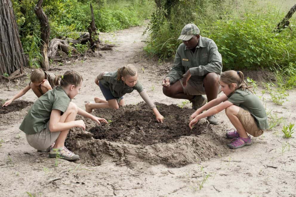 Children playing in the sand during an educational bush safari activity in Mana Pools National Park.
