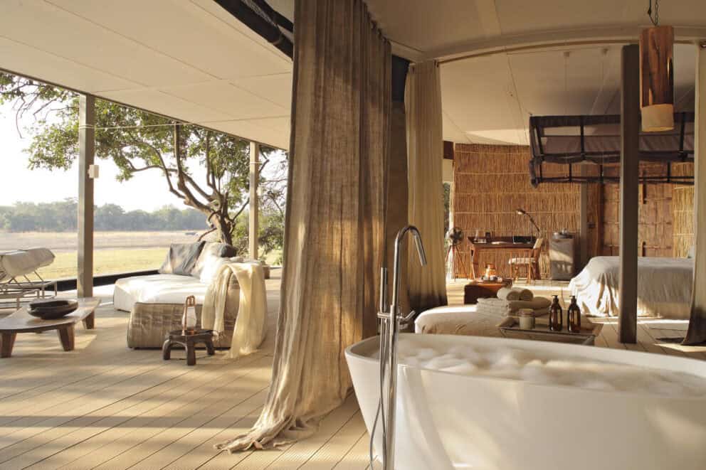 View of the Luangwa River from the luxury bedroom suite, featuring a freestanding bath and private deck at Chinzombo, Zambia.