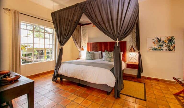 View of the bedroom suite, featuring a canopied bed with luxury insect netting draped over at Shongwe Lookout, Zimbabwe.
