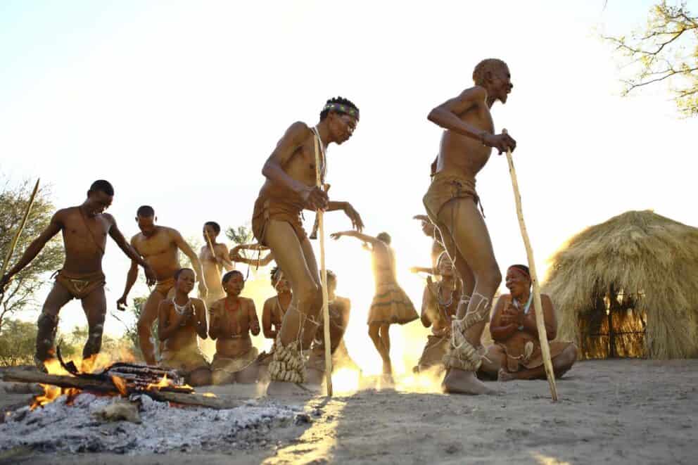 Bushmen dancing around a fire as the sun sets at Feline Fields Lodge, Botswana.