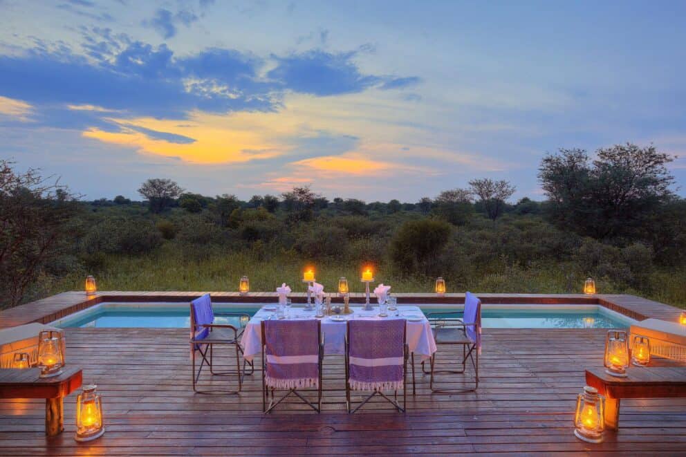 A lantern-lit private dining set up by the pool under the African night sky at Feline Fields Lodge, Botswana.