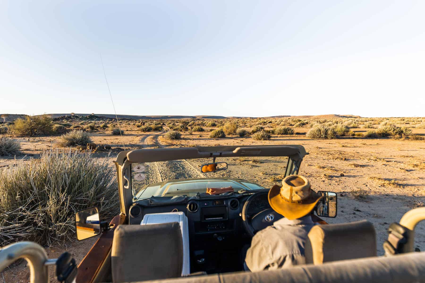 Open-air safari vehicle driving through a desert landscape in Fish River Canyon, Namibia