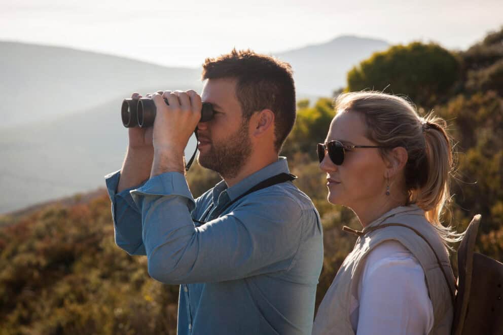 Couple watching birds with binoculars on a guided nature walk at Grootbos Forest Lodge.