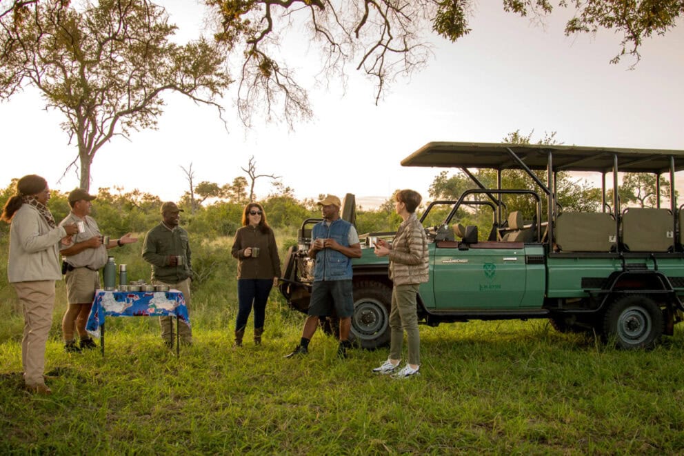 A group of tourists enjoying a coffee break at sunrise in the bush at Lukimbi Safari Lodge, South Africa.