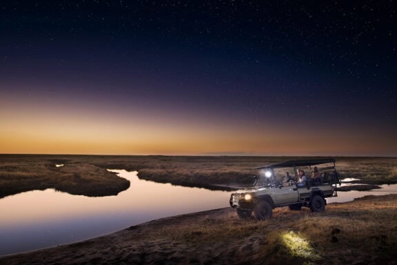 Guests on a night drive in a safari vehicle near Linyanti Bush Camp in the LInyanti Concession, Botswana.