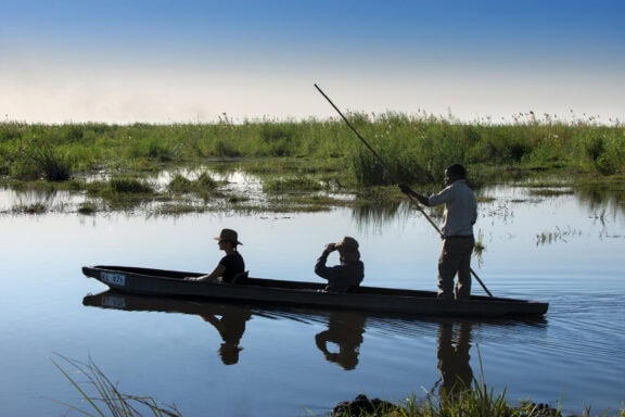 Guests on a guided mokoro ride along the waterways near Linyanti Bush Camp in the Linyanti Concession, Botswana.