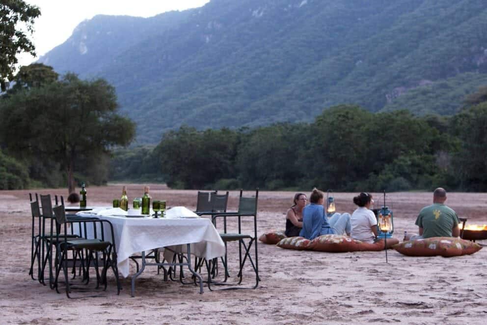 Guests seated on pillows overlooking the African landscape near Wayo Manyara Green Camp in Lake Manyara National Park, Tanzania.