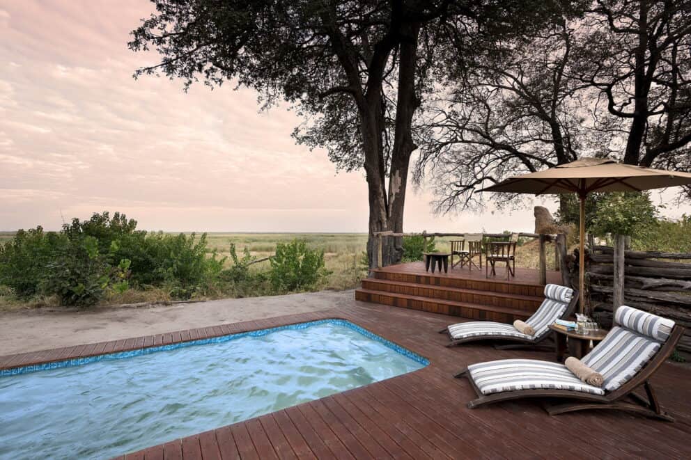 Wooden pool deck at Linyanti Bush Camp featuring sun loungers overlooking the African landscape.