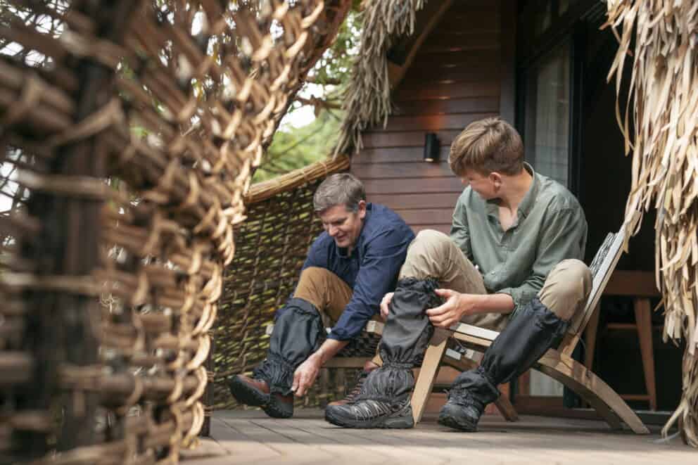 Guests prepping their hiking boots on a terrace, preparing for a guided mountain gorilla trek at Wilderness Bisate in Volcanoes National Park, Rwanda.