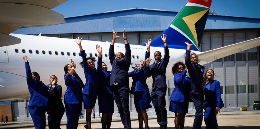Group of people jumping in front of a plane