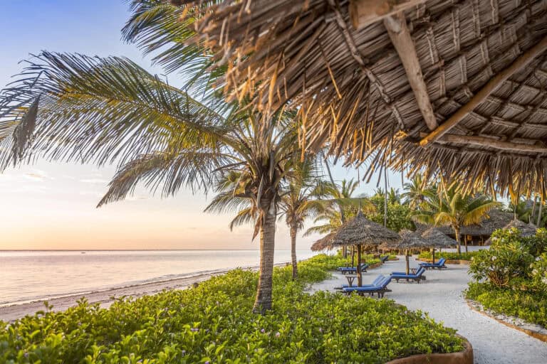 View of the beach from the deck, featuring pool loungers at Breezes Beach Club and Spa, Zanzibar.